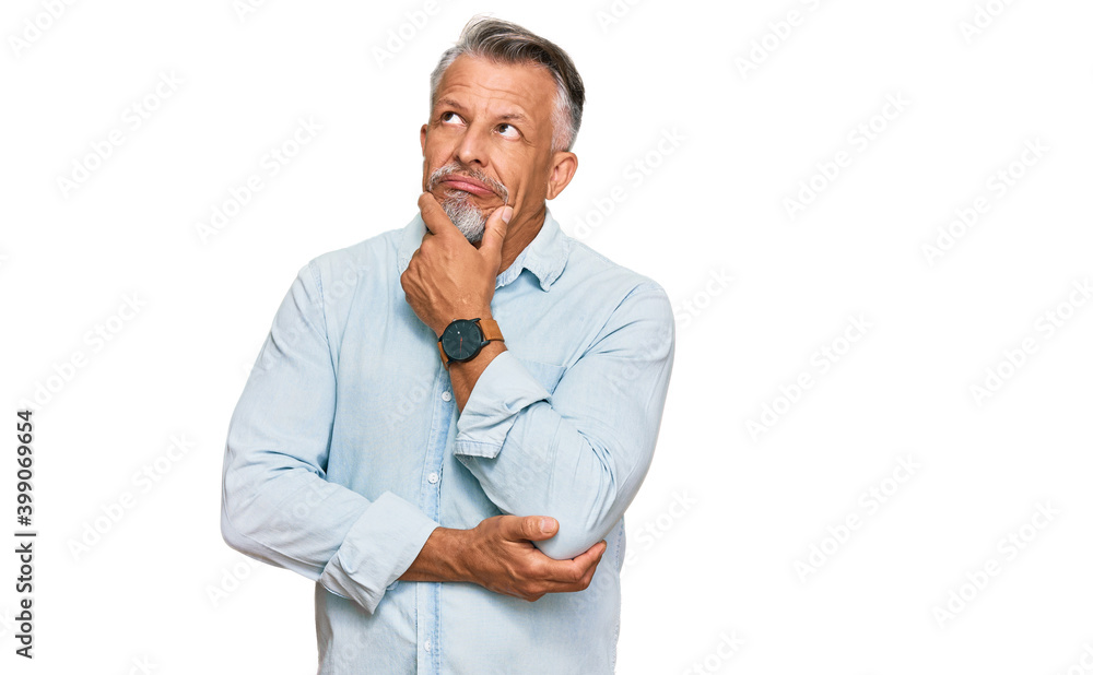 Middle age grey-haired man wearing casual clothes thinking worried about a question, concerned and nervous with hand on chin Middle age grey-haired man wearing casual clothes thinking worried about a question, concerned and nervous with hand on chin