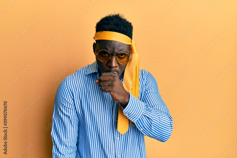 Handsome black man drunk wearing tie over head and sunglasses feeling unwell and coughing as symptom for cold or bronchitis. health care concept. Handsome black man drunk wearing tie over head and sunglasses feeling unwell and coughing as symptom for cold or bronchitis. health care concept.