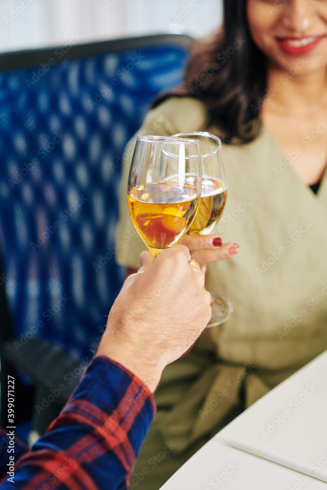 Close-up image of business colleagues clinking champagne glasses over office table Close-up image of business colleagues clinking champagne glasses over office table