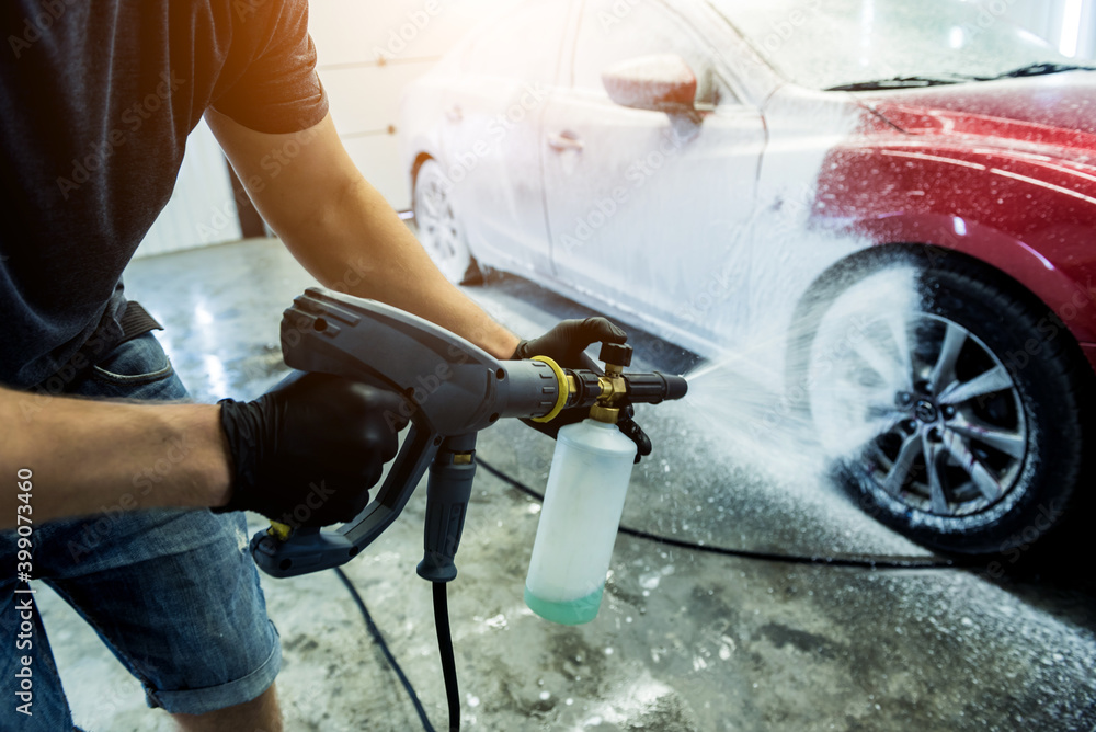 Obraz premium Worker washing car with active foam on a car wash.