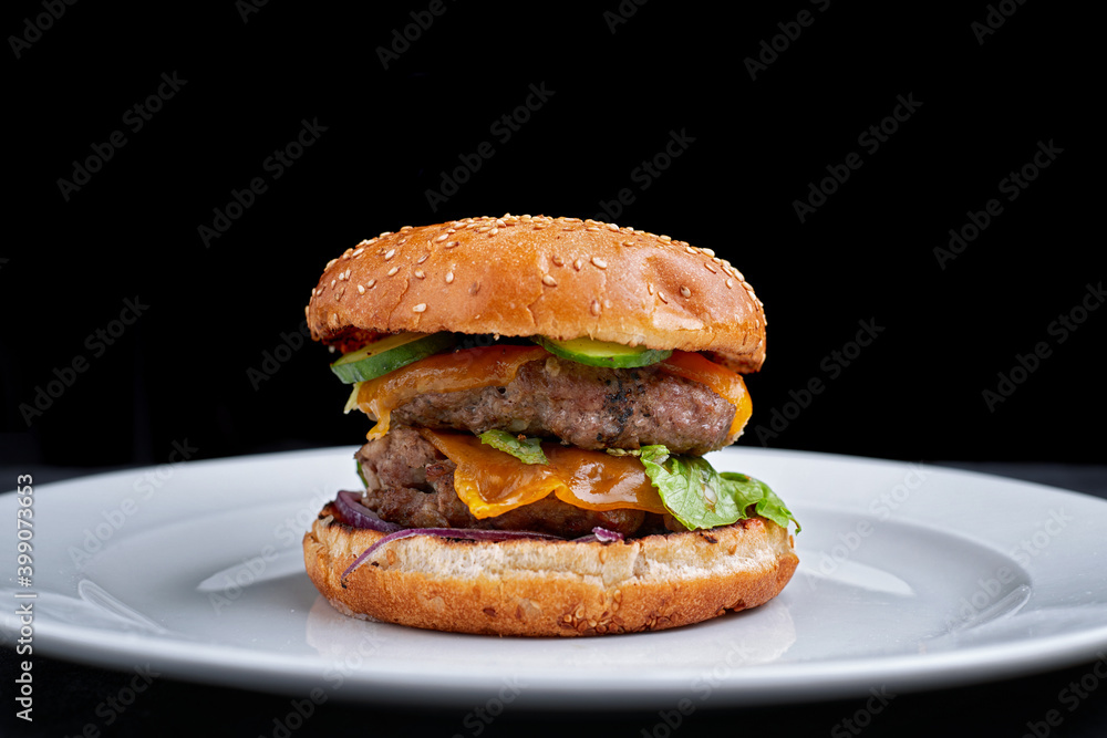 Burger with double meat cutlet, cheese. cucumber, and lettuce, on a white plate, on a black background Burger with double meat cutlet, cheese. cucumber, and lettuce, on a white plate, on a black background