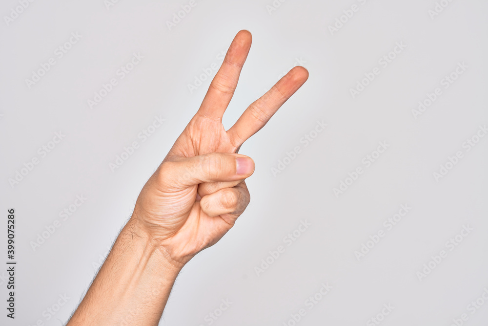Hand of caucasian young man showing fingers over isolated white background counting number 2 showing two fingers, gesturing victory and winner symbol Hand of caucasian young man showing fingers over isolated white background counting number 2 showing two fingers, gesturing victory and winner symbol