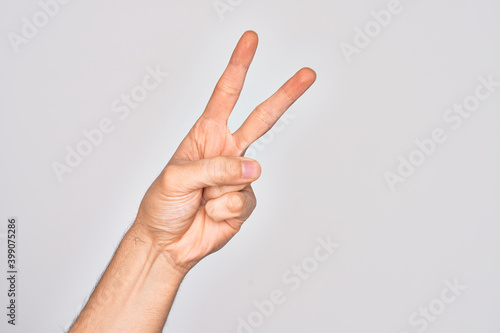 Hand of caucasian young man showing fingers over isolated white background counting number 2 showing two fingers, gesturing victory and winner symbol