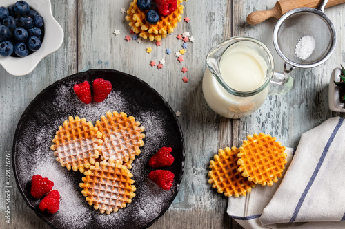 blueberries, raspberries and waffles on a rustic white wooden background