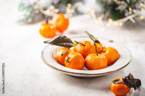 Fresh mandarin fruit or tangerines with leaves in a bowl on white background with winter decorations