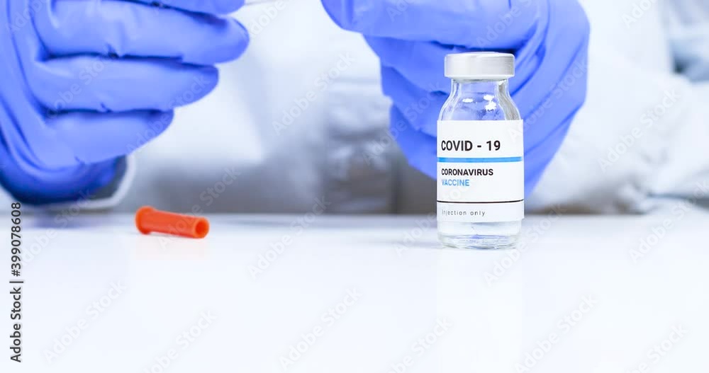 Close-up of female doctor hands in blue medical gloves with transparent liquid coronavirus vaccine bottle and syringe for injection in the laboratory. Research and development of new cure for diseases Close-up of female doctor hands in blue medical gloves with transparent liquid coronavirus vaccine bottle and syringe for injection in the laboratory. Research and development of new cure for diseases