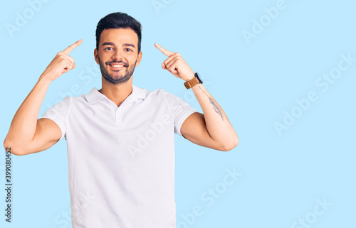 Young handsome hispanic man wearing casual clothes smiling pointing to head with both hands finger, great idea or thought, good memory