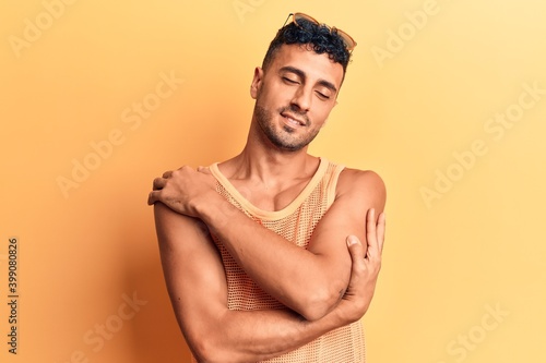 Young hispanic man wearing casual clothes hugging oneself happy and positive, smiling confident. self love and self care