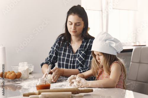 Family in a kitchen. Beautiful mother with little daughter. Woman in a black shirt.