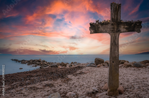 Big wooden cross at the seaside while coloful sunset