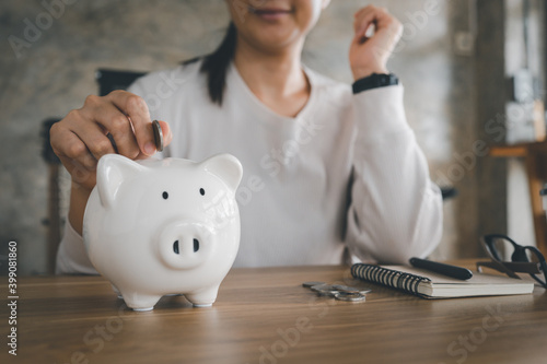 Happy smart asian woman saving money in a piggybank. saving and money concept.