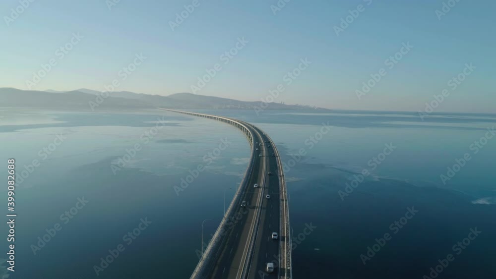 Aerial drone view of low-water bridge across the bay with moving car. Active movement of transport cars vehicles in different directions.