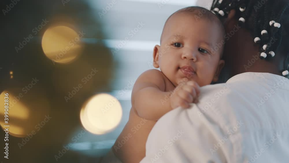 Beautiful newborn baby enjoying hugs from his black father near christmas tree. Holidays in multiracial family. High quality 4k footage Beautiful newborn baby enjoying hugs from his black father near christmas tree. Holidays in multiracial family. High quality 4k footage
