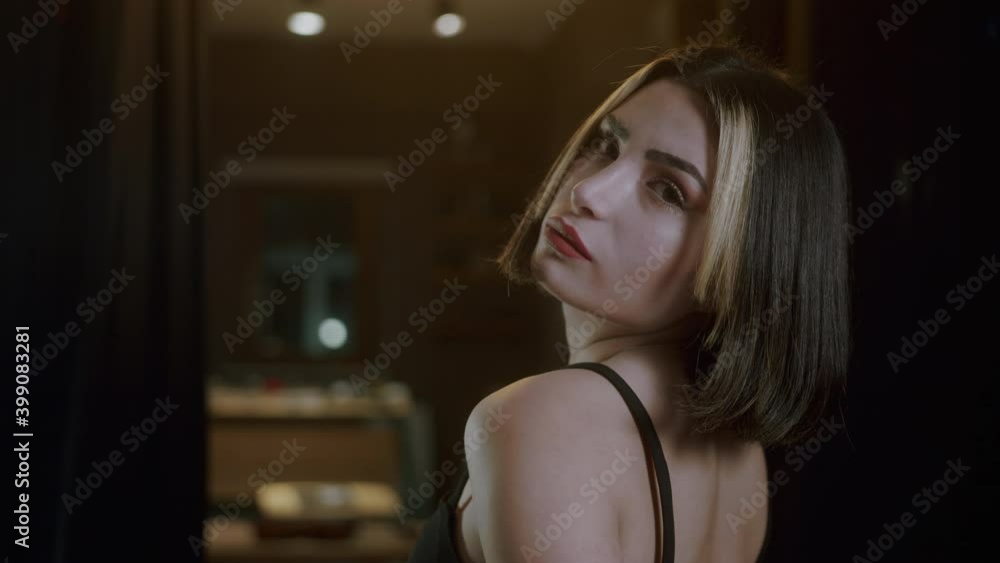 Young beautiful and attractive woman with short hair in a black dress turns her back and poses for the camera. Close-up 4K Young beautiful and attractive woman with short hair in a black dress turns her back and poses for the camera. Close-up 4K