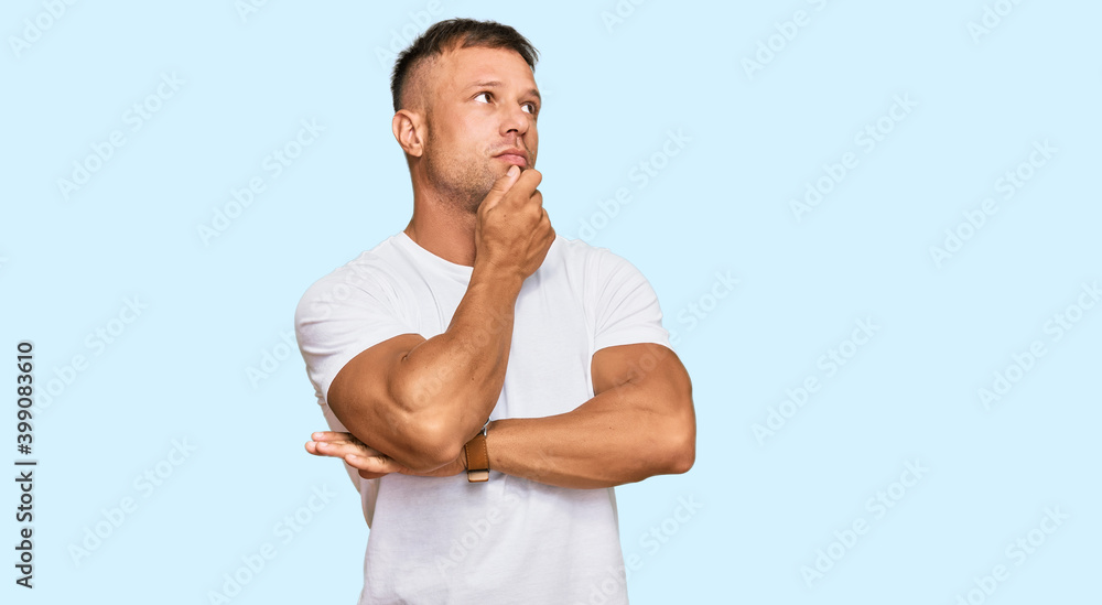 Handsome muscle man wearing casual white tshirt with hand on chin thinking about question, pensive expression. smiling with thoughtful face. doubt concept. Handsome muscle man wearing casual white tshirt with hand on chin thinking about question, pensive expression. smiling with thoughtful face. doubt concept.