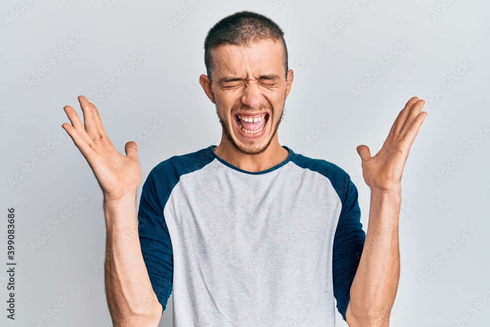 Hispanic young man wearing casual clothes celebrating mad and crazy for success with arms raised and closed eyes screaming excited. winner concept Hispanic young man wearing casual clothes celebrating mad and crazy for success with arms raised and closed eyes screaming excited. winner concept
