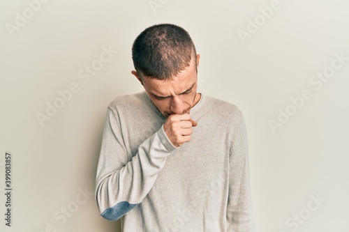 Hispanic young man wearing casual winter sweater feeling unwell and coughing as symptom for cold or bronchitis. health care concept.