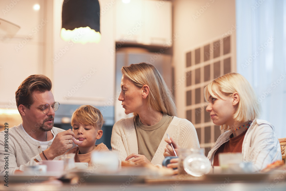 Portrait of modern happy family enjoying breakfast together sitting at table in cozy kitchen interior, parents with two children, copy space Portrait of modern happy family enjoying breakfast together sitting at table in cozy kitchen interior, parents with two children, copy space
