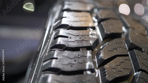 Smooth slowmotion close-up shot of a brand new car tyre, focus pulled.