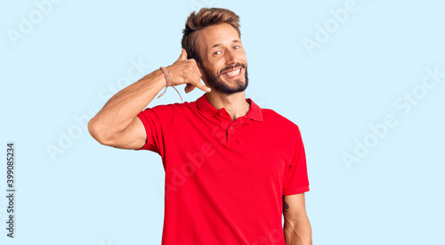 Handsome blond man with beard wearing casual clothes smiling doing phone gesture with hand and fingers like talking on the telephone. communicating concepts.