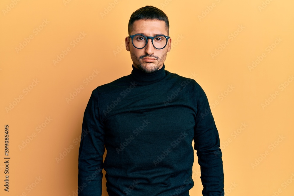 Handsome man with tattoos wearing turtleneck sweater and glasses depressed and worry for distress, crying angry and afraid. sad expression. Handsome man with tattoos wearing turtleneck sweater and glasses depressed and worry for distress, crying angry and afraid. sad expression.