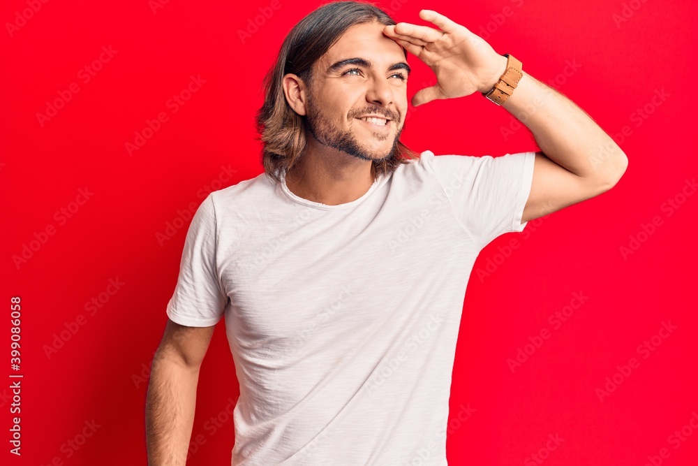 Fototapeta premium Young handsome man wearing casual clothes very happy and smiling looking far away with hand over head. searching concept.
