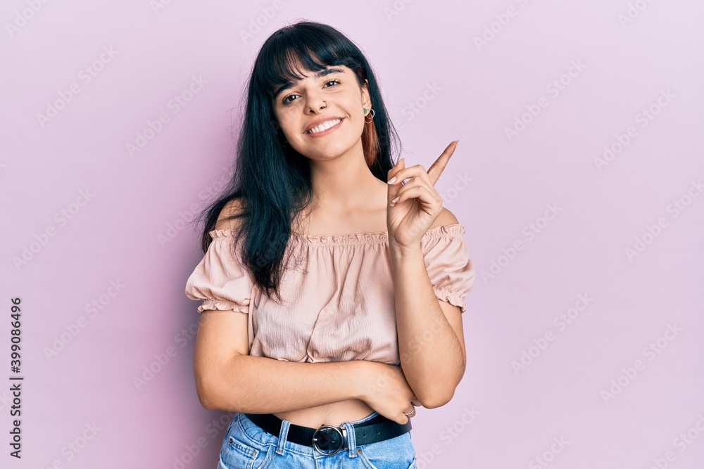 Fototapeta premium Young hispanic girl wearing casual clothes with a big smile on face, pointing with hand and finger to the side looking at the camera.