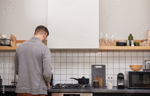 Back view at modern adult man cooking dinner while standing at counter in kitchen interior, copy space