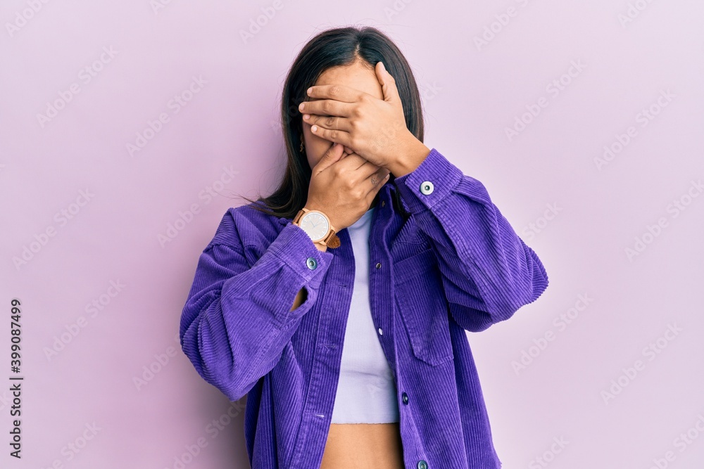 Young brunette woman wearing casual clothes covering eyes and mouth with hands, surprised and shocked. hiding emotion Young brunette woman wearing casual clothes covering eyes and mouth with hands, surprised and shocked. hiding emotion