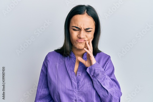 Young brunette woman wearing casual clothes touching mouth with hand with painful expression because of toothache or dental illness on teeth. dentist
