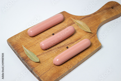 Sausages on a wooden board. Three sausages are lying next to each other. meat product on a white background.
