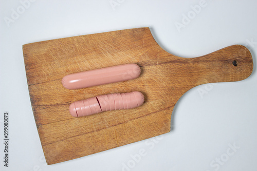 Sausages on a wooden board. A chopped sausage next to a whole sausage. meat product on a white background.
