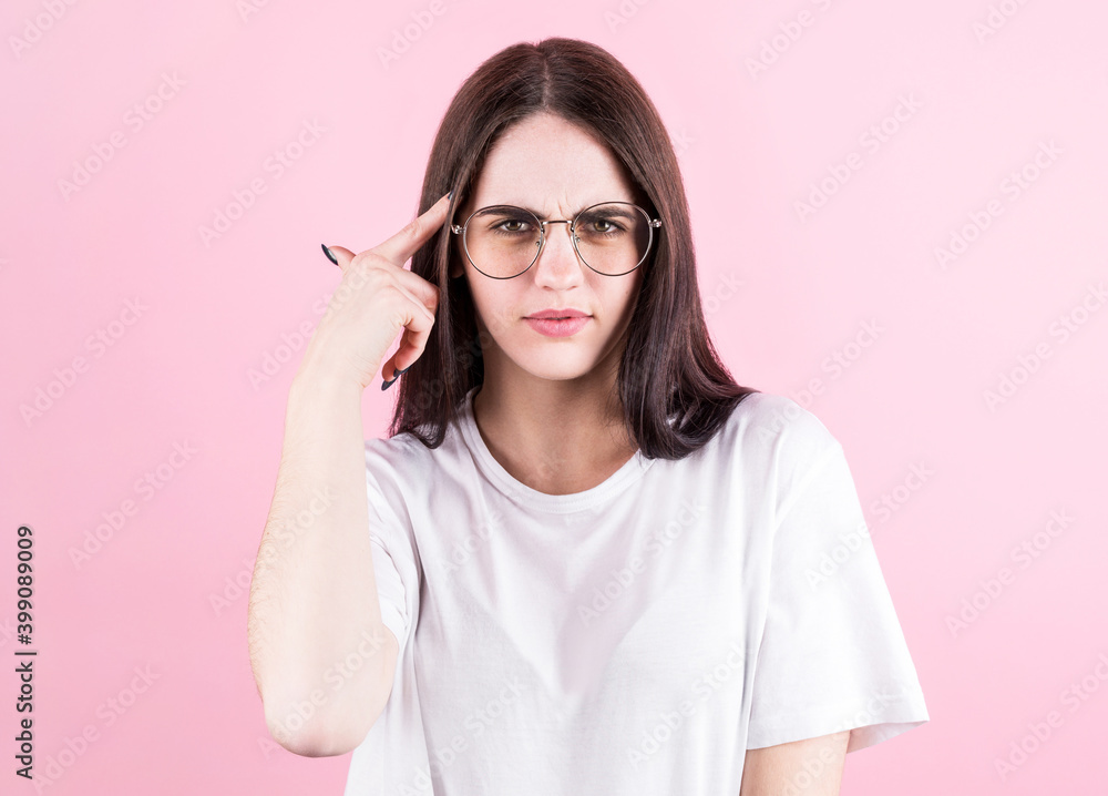 Portrait of young woman thinking with her finger to her head isolated over pink background Portrait of young woman thinking with her finger to her head isolated over pink background