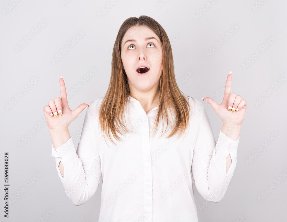 Image of happy young lady standing isolated over white background, looking up and pointing. Image of happy young lady standing isolated over white background, looking up and pointing.