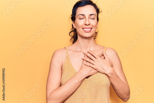 Young beautiful hispanic woman wearing casual clothes smiling with hands on chest with closed eyes and grateful gesture on face. health concept.