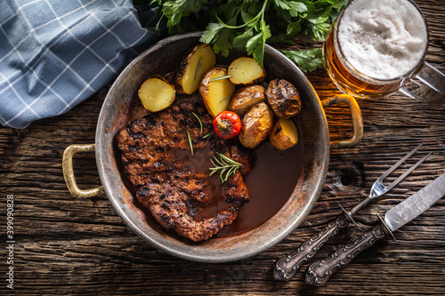 Top view of baked pork nech with potaties served in metallic vintage bowl and beer photo