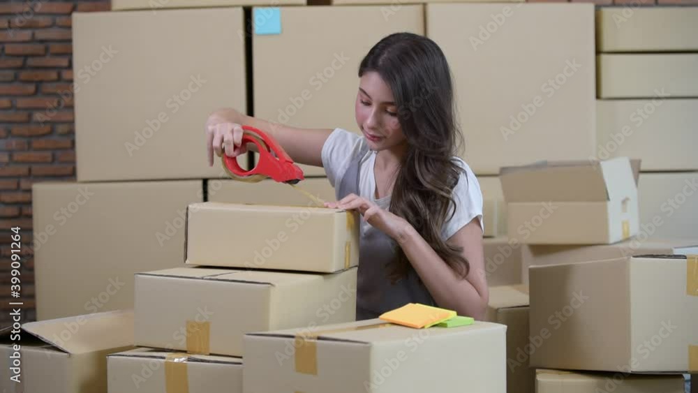 Startup small business owner working at home, women sealing cardboard box with adhesive tape, Online shopping business, ecommerce and delivery to customer concept Startup small business owner working at home, women sealing cardboard box with adhesive tape, Online shopping business, ecommerce and delivery to customer concept