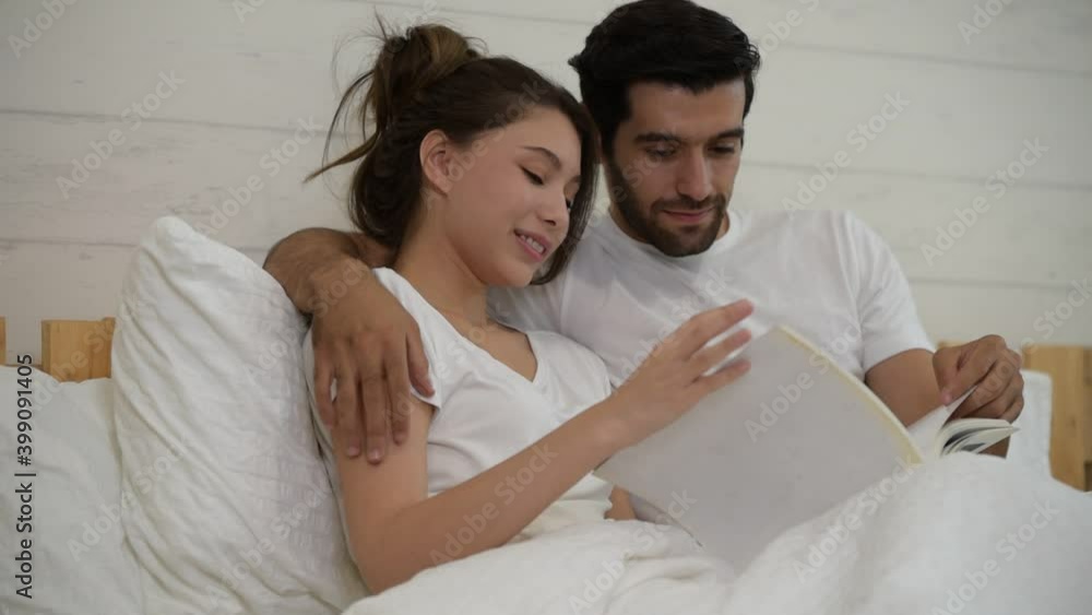 Happy young relaxed loving couple lying on the bed and reading books together at home Happy young relaxed loving couple lying on the bed and reading books together at home