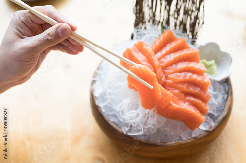 A set of sushi on a wooden table in a Japanese restaurant.Fresh salmon sliced for sushi menu.Party of friends or family eating sushi using bamboo sticks.