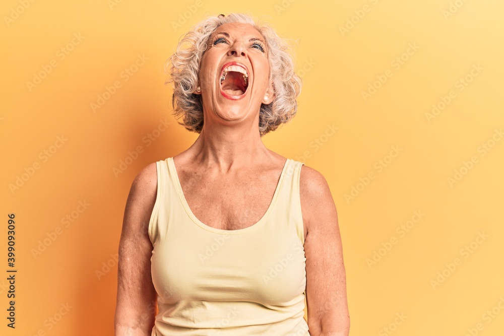 Senior grey-haired woman wearing casual clothes angry and mad screaming frustrated and furious, shouting with anger. rage and aggressive concept. Senior grey-haired woman wearing casual clothes angry and mad screaming frustrated and furious, shouting with anger. rage and aggressive concept.