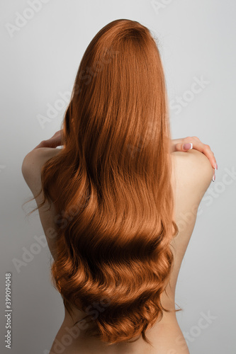 Photo wavy red hair back view. Grey background