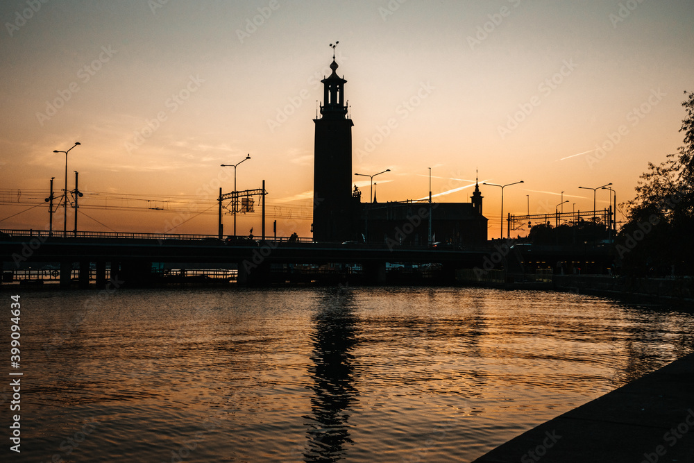Beautiful view of the Stockholm City Hall during sunrise. Contrasting dark silhouette against the orange sky. Stockholm, Sweden