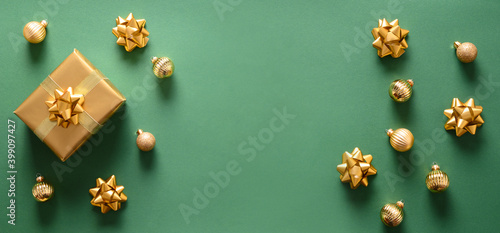 Christmas banner with golden gift and balls on green background. Top view. Xmas or New Year greeting card with copy space.