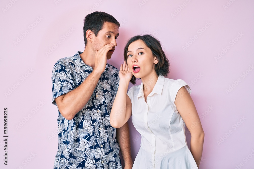 Beautiful couple wearing casual clothes hand on mouth telling secret rumor, whispering malicious talk conversation Beautiful couple wearing casual clothes hand on mouth telling secret rumor, whispering malicious talk conversation