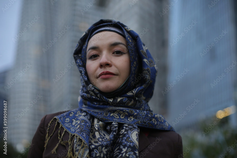 Medium shot pictures of beautiful model using hijab with office buildings in the back
