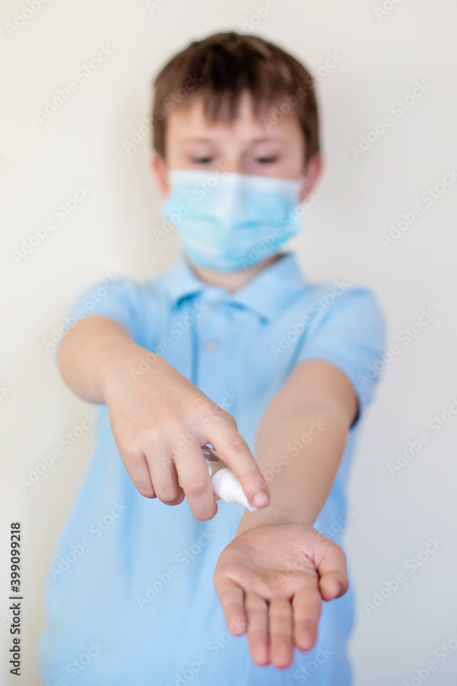 boy in protective medical mask splashes transparent antiseptic on hands. Hand disinfection during coronavirus epidemic. Personal hygiene. Virus protection concept.