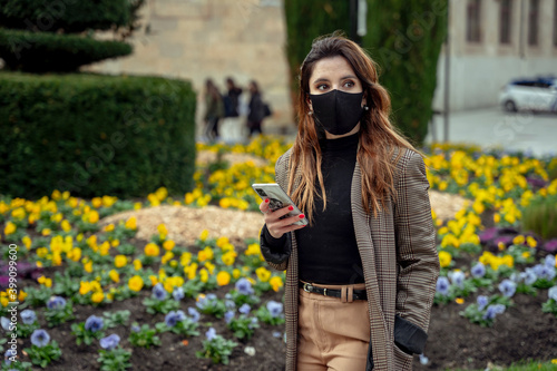 Girl watching a phone wearing a mask with flower background
