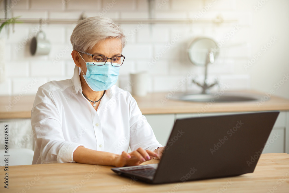 adult woman in glasses and in a medical gown at the table with a laptop adult woman in glasses and in a medical gown at the table with a laptop