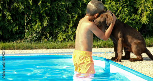 Obraz na płótnie Little boy playing with a dog by the pool. Labrador puppy with baby in the garden. w salonie