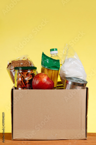 Food Donation concept. Donation Box With food For Donation On Yellow Backround. Assistance To The Elderly In The Context of The Coronavirus Pandemic. Vertical shot.